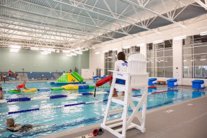Indoor pool with lifeguard looking on